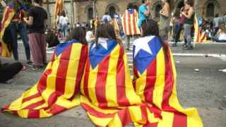 Tres jóvenes con esteladas en la espalda durante una manifestación de la Diada de Cataluña.