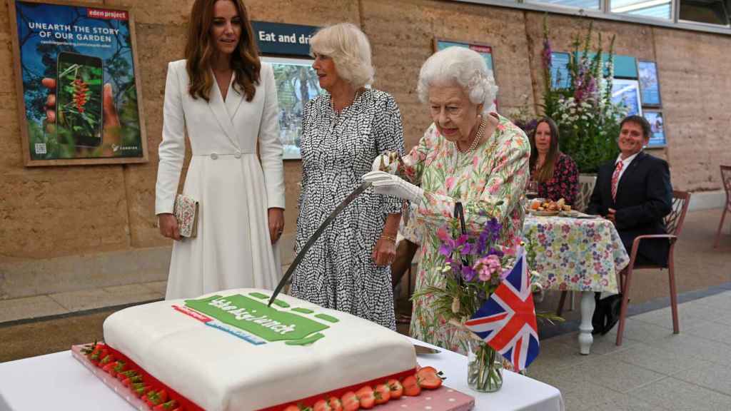 La reina Isabel II, cortando una tarta, junto a Kate Middleton y Camilla Parker.