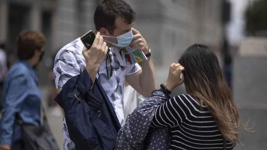 Dos personas se colocan la mascarilla