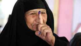 Una mujer muestra su dedo con tinta después de haber votado en Irak.