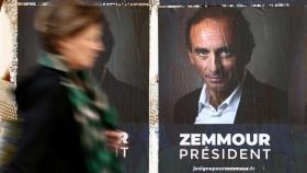 A woman walks past posters in support of French far-right commentator Eric Zemmour in Paris