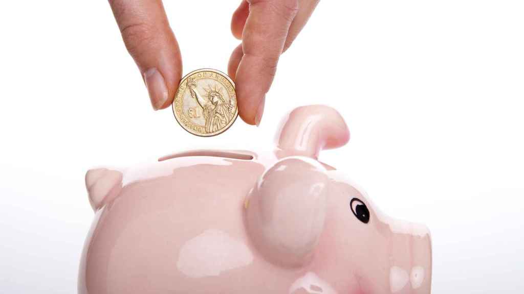 Un ahorrador inserta una moneda en una hucha.