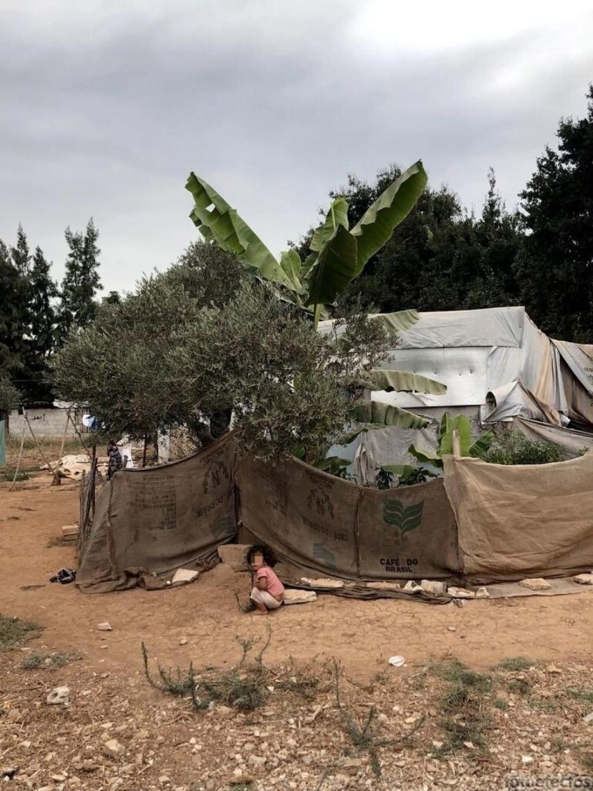 Una niña juega en un campamento informal cerca de la ONG.