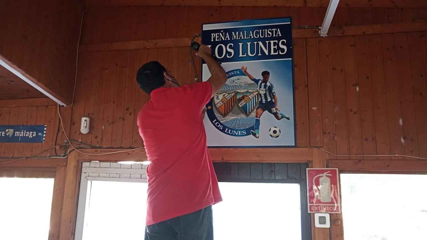Un integrante de la Peña Malaguista Los Lunes retira uno de los carteles en la sede.