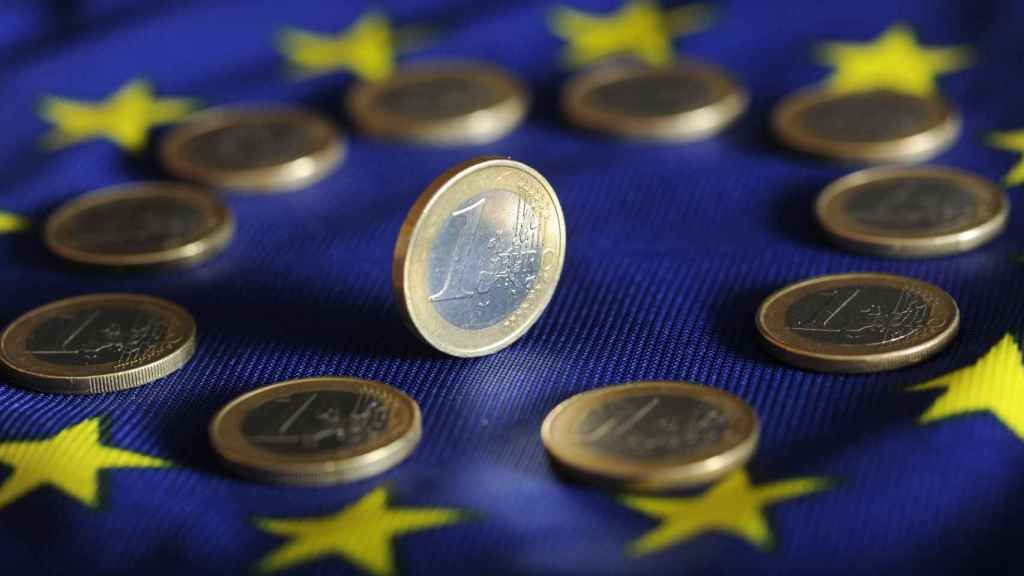 Monedas de un euro sobre una bandera de la Unión Europea.