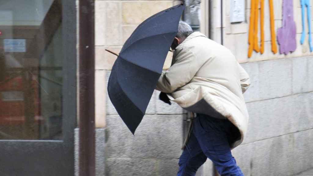 Un hombre se guarece del viento con su paraguas
