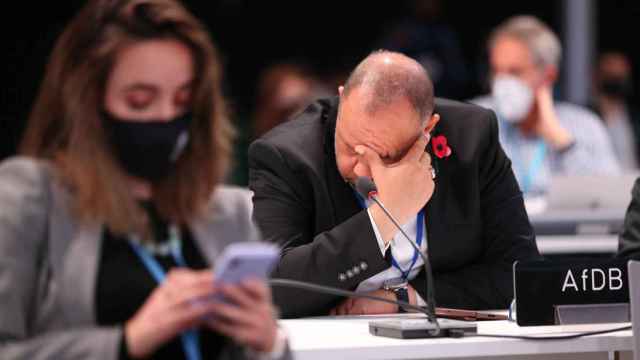 Delegados de los países que participan en la COP26 reaccionan durante las negociaciones.