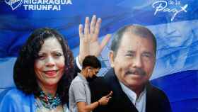 Un hombre delante de un cartel electoral  de Daniel Ortega, y su mujer, la vicepresidenta, Rosario Murillo.