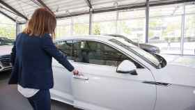 Una mujer prueba un coche antes de comprarlo en un concesionario.