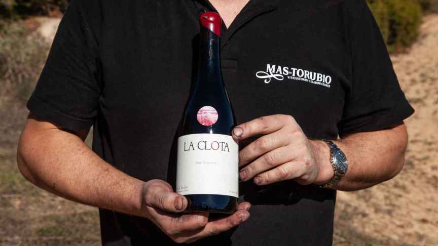 Con las manos manchadas de tierra, Monreal enseña una de las 30.000 botellas de vino que produce al año.