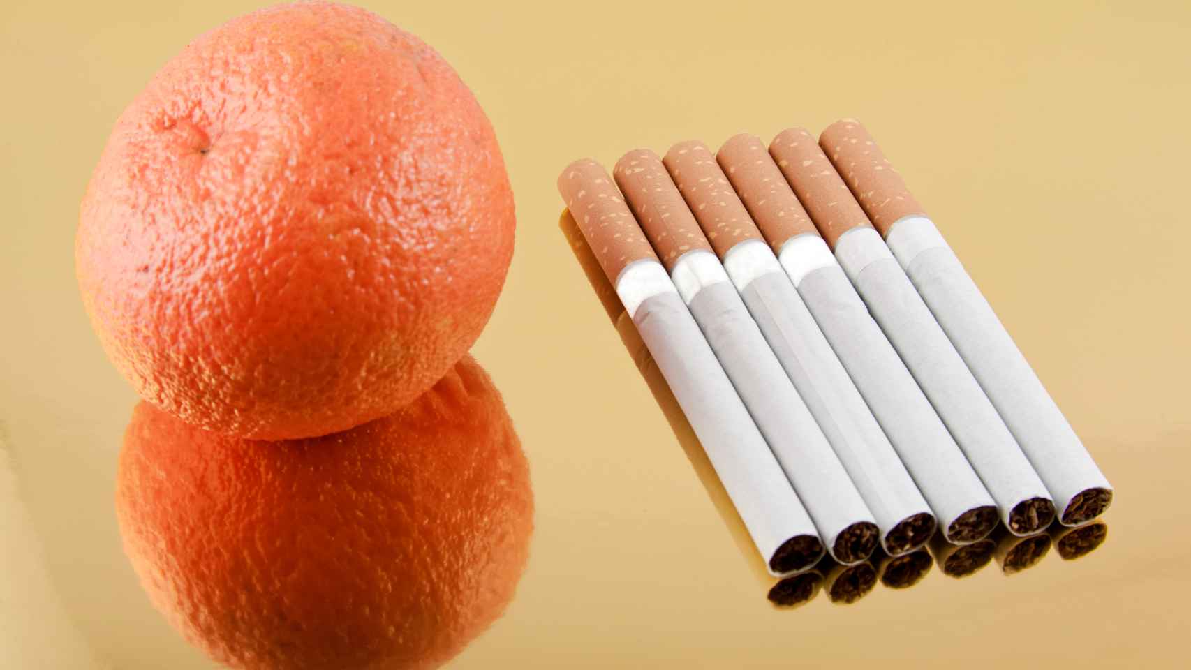 Una mandarina junto a seis cigarrillos.