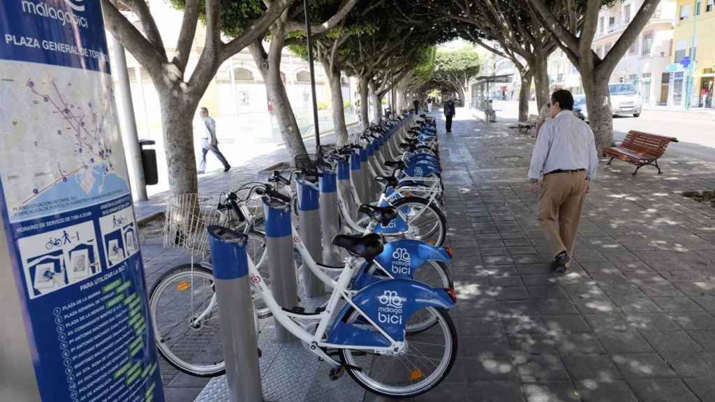 Una persona pasa junto a una de las estaciones del sistema de bicis de alquiler de Málaga, que deja de funcionar.