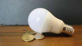 Imagen de una bombilla sobre un montón de monedas.