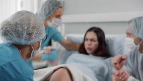 Una mujer da a luz en un hospital asistida por médicos y enfermeras.