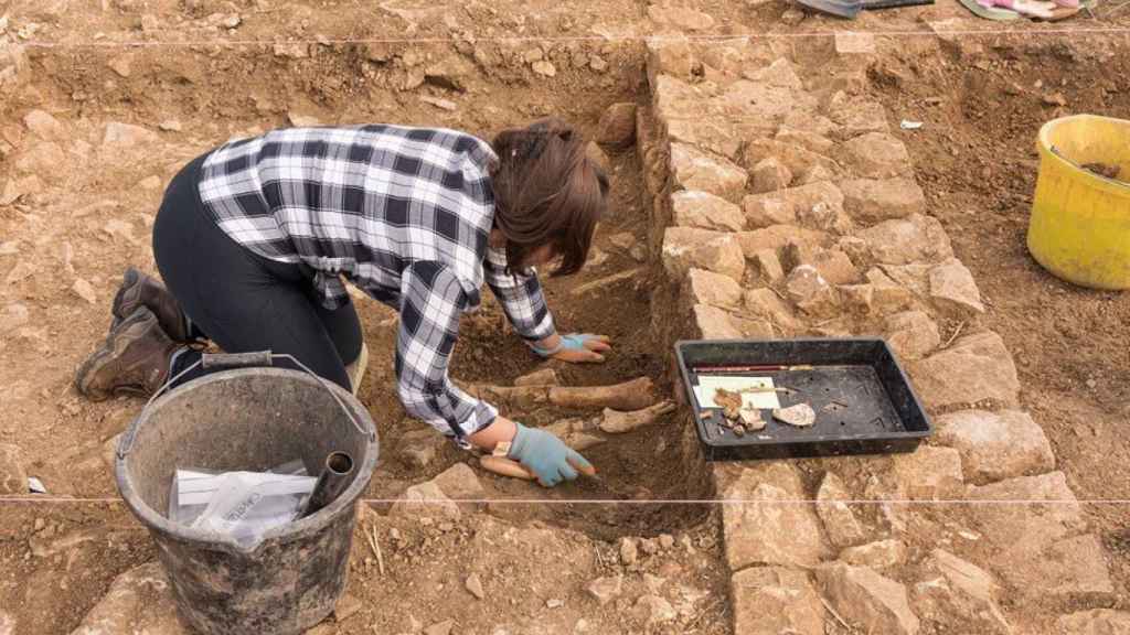 Un arqueólogo recoge los restos humanos encontrados sobre el mosaico romano.
