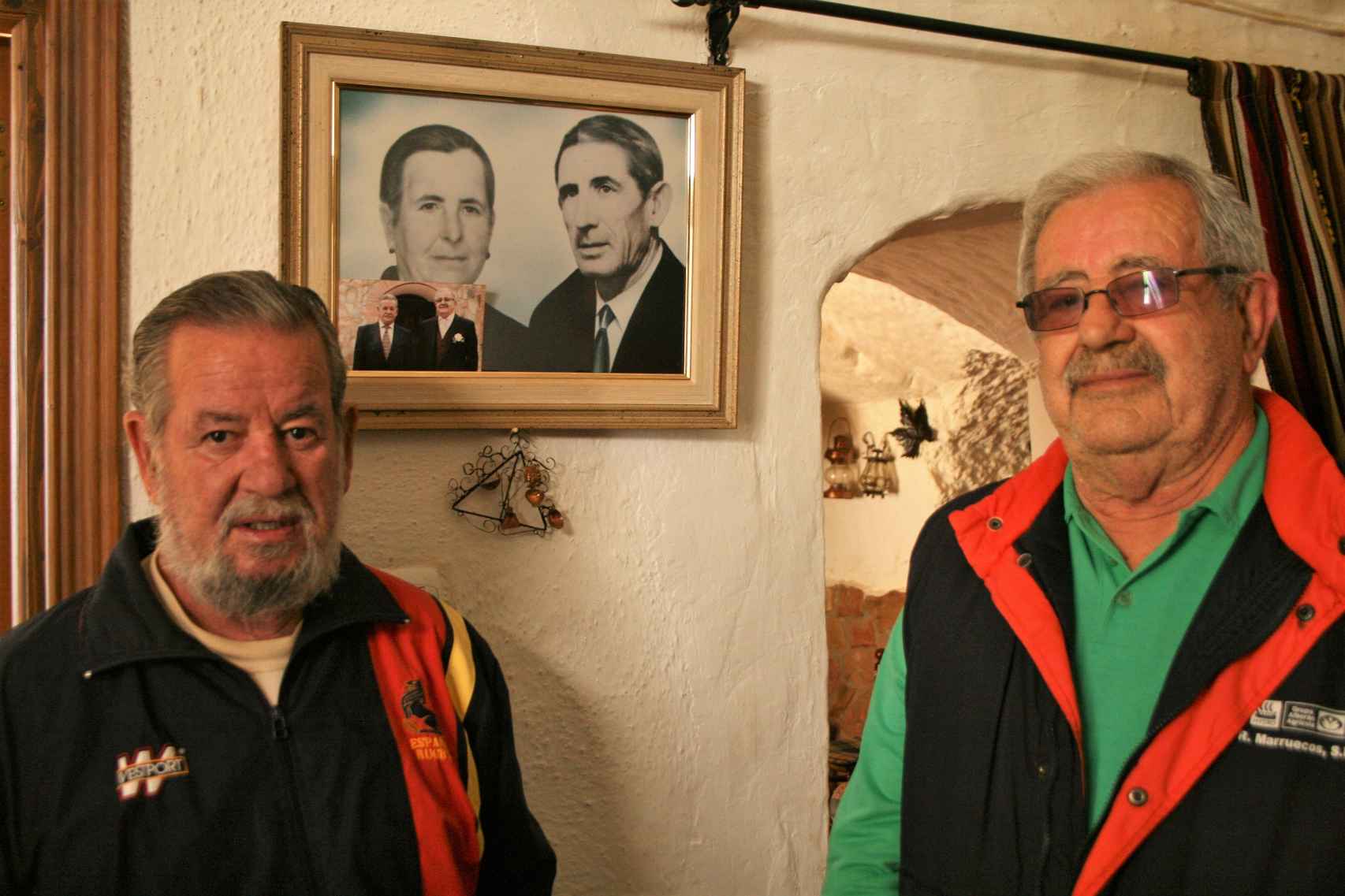 Ramón y Manuel Rodríguez, en su cueva natal en Paulenca, presidida por el retrato de sus padres.