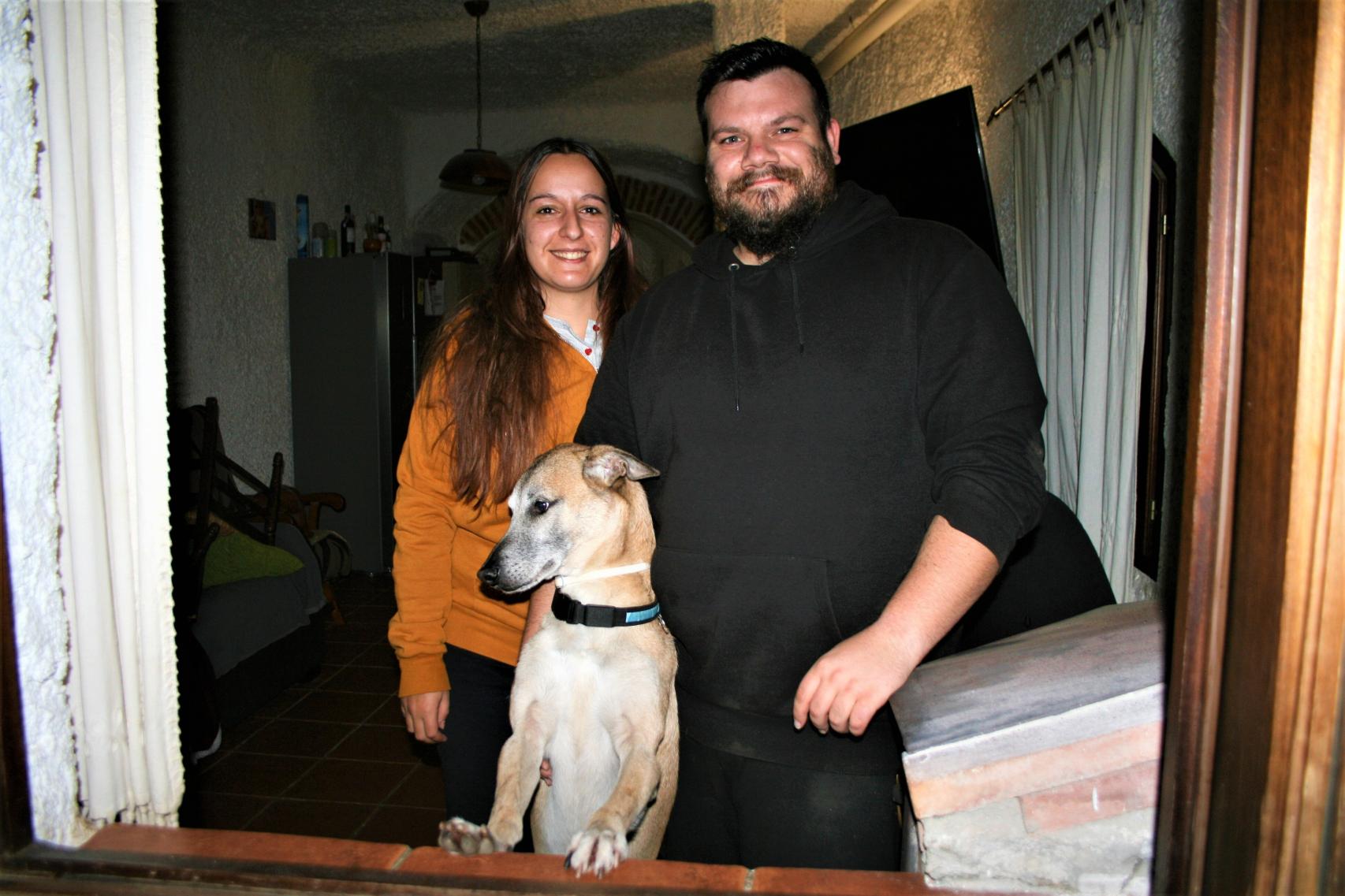 Rocío Picazo y Juan Llorente se asoman con su perro a la ventana de su cueva de alquiler.