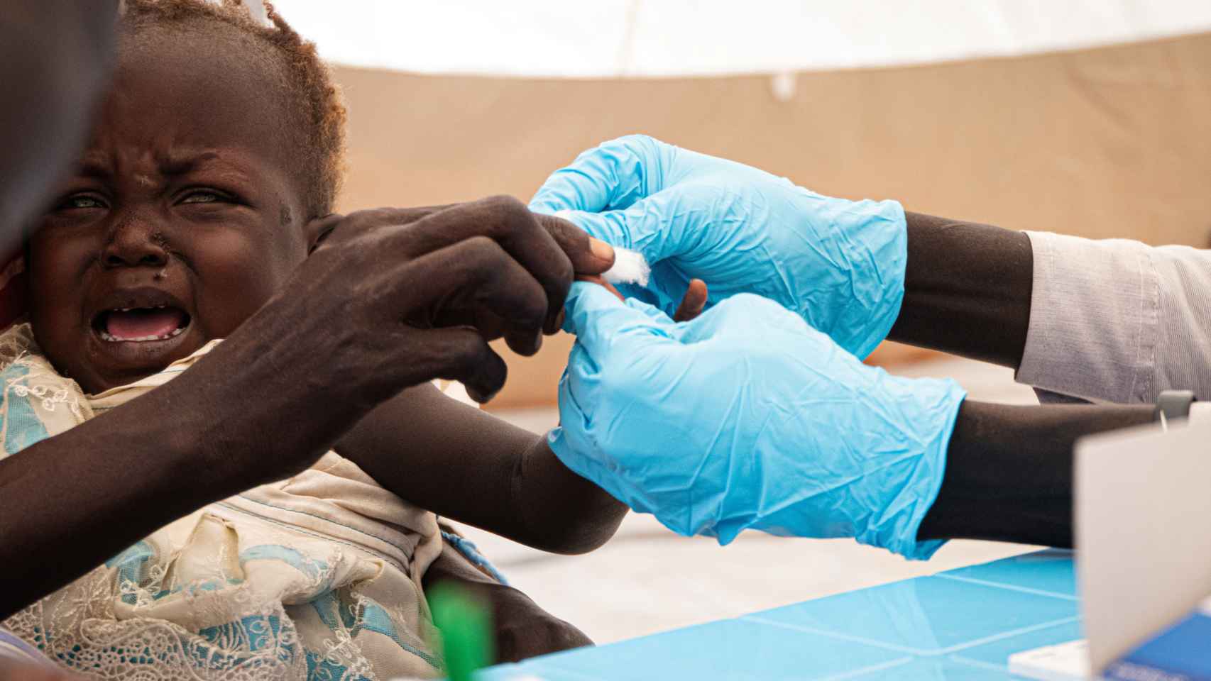 Un niño llora mientras le hacen la prueba para ver si tiene malaria en Sudán.