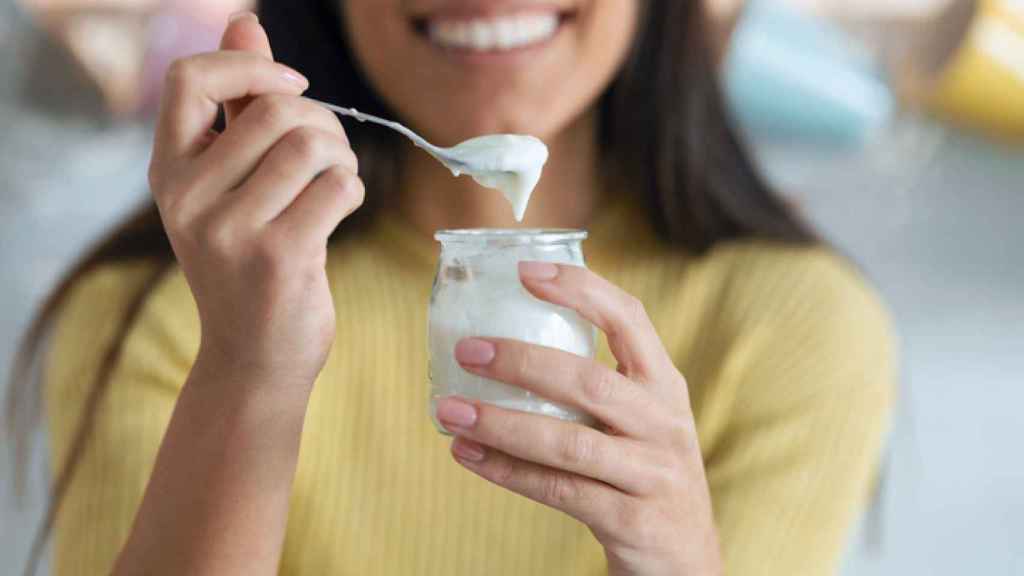 Una mujer comiendo un yogur desnatado.