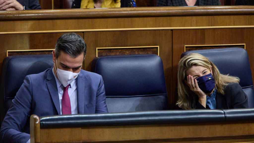 Yolanda Díaz ríe en su escaño azul del Gobierno, junto a Pedro Sánchez, en el Congreso de los Diputados.