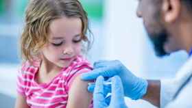 Un médico vacuna a una niña.