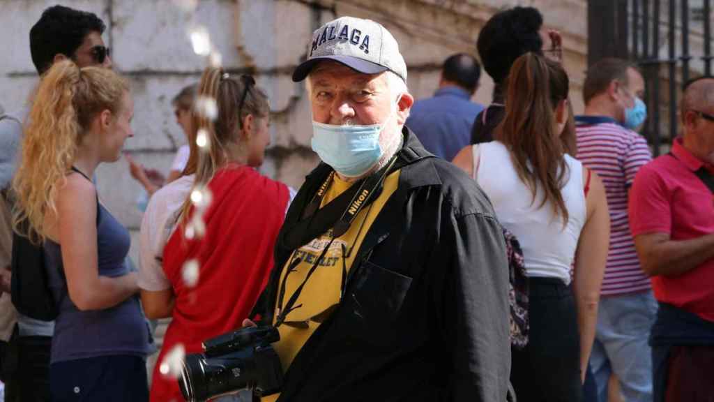 Un hombre, con una mascarilla y una gorra de Málaga