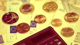 Billetes y monedas de euro junto a una calculadora.