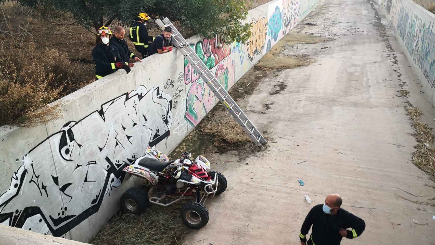 Imagen de los bomberos y del quad accidentado dentro de un arroyo en Málaga.