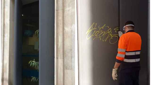 Un empleado limpia la fachada del edificio del Ayuntamiento en Alicante.