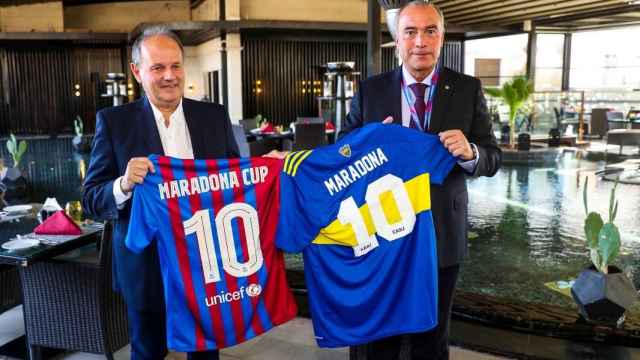 Rafa Yuste y un directivo de Boca Juniors sostienen camisetas de Diego Armando Maradona.