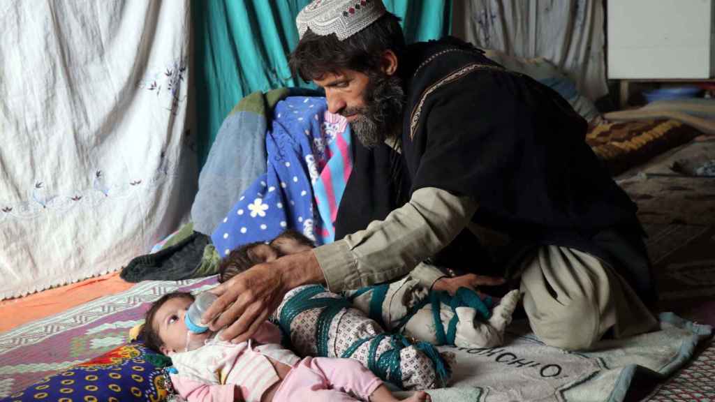 Un padre alimenta a sus dos hijas en Afganistán.