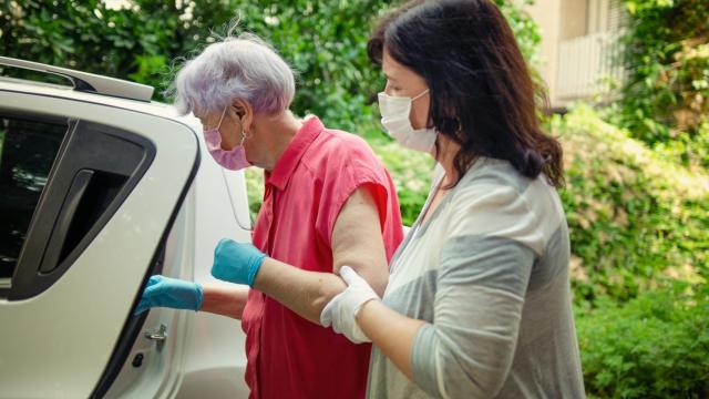 Una anciana con problemas de movilidad precisa de ayuda para subir al coche.