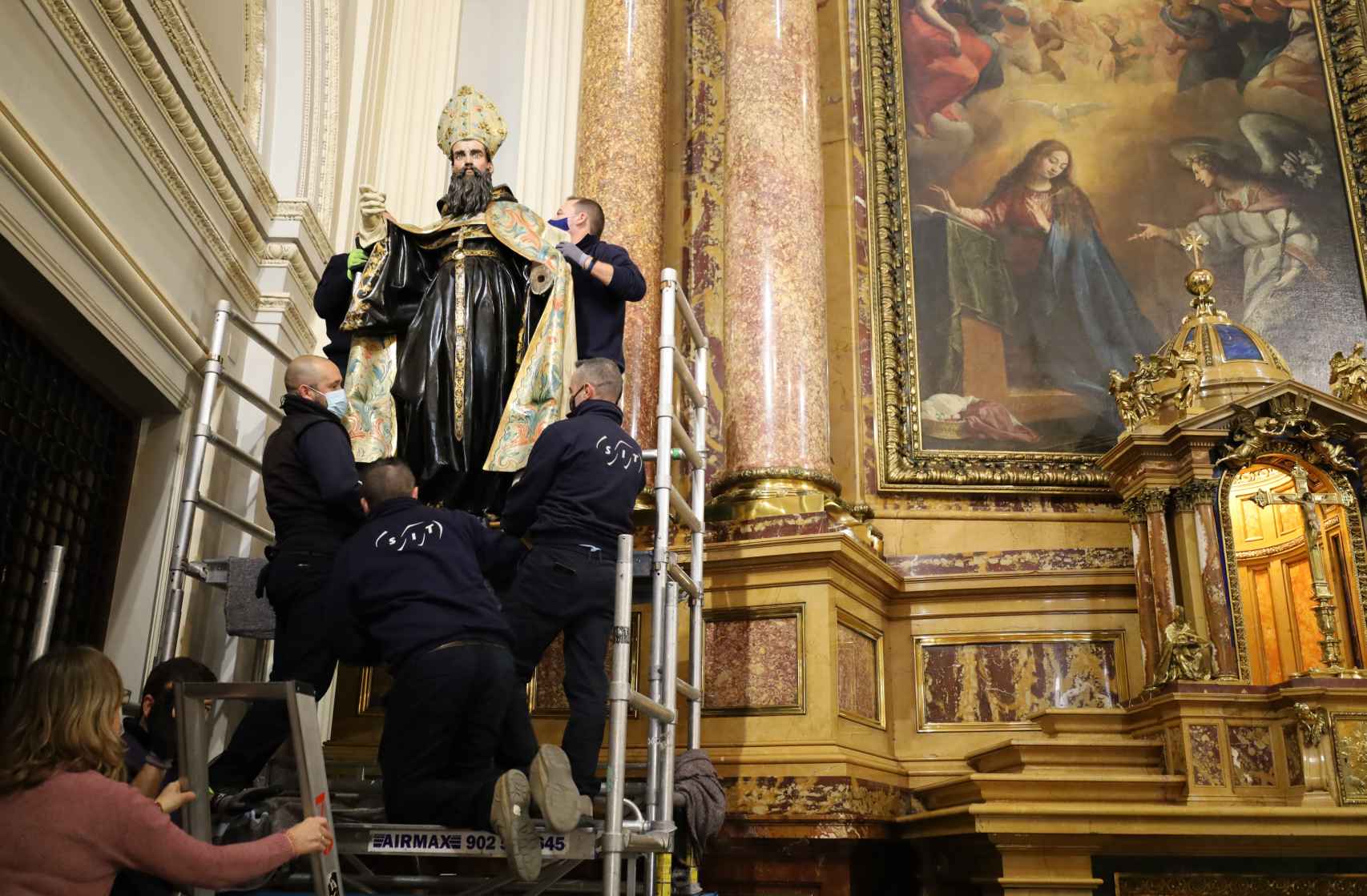 Los operarios colocan a 'San Agustín' en su peana del retablo.