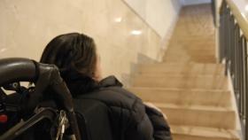 Una chica en silla de ruedas frente a unas escaleras