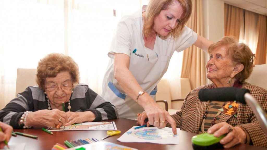 Personal cualificado atiende a dos mujeres mayores en una residencia