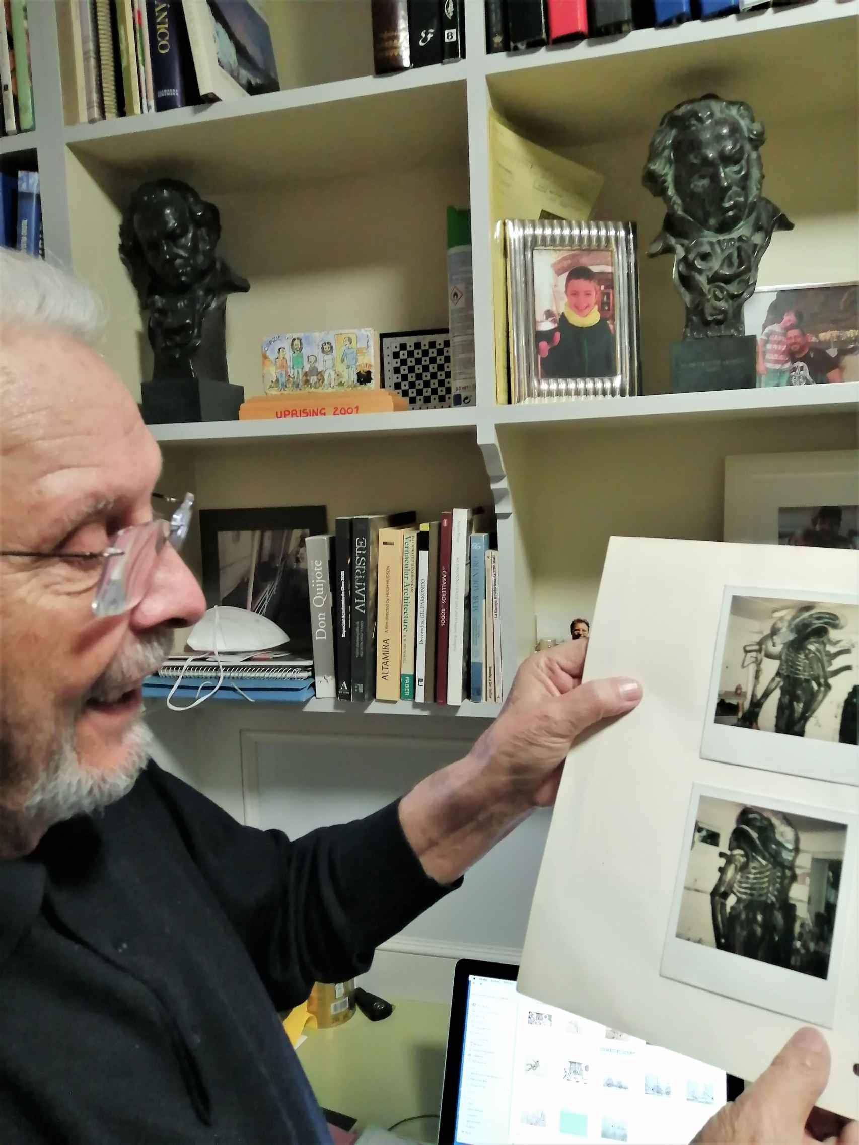 El director de arte enseña unas fotos de 'Alien'; al fondo, en la estantería, sus dos Goya.