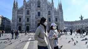 Dos personas pasean con mascarilla en Milán. EP