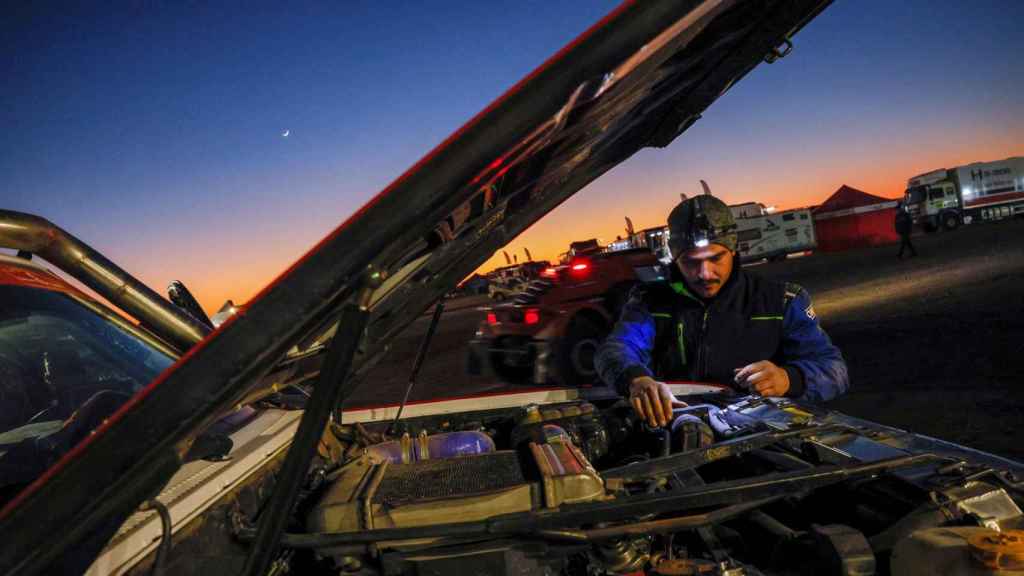 Un mecánico trabaja al atardecer al finalizar la tercera etapa del Rally Dakar 2022, este martes en Al Qaisumah, Arabia Saudí