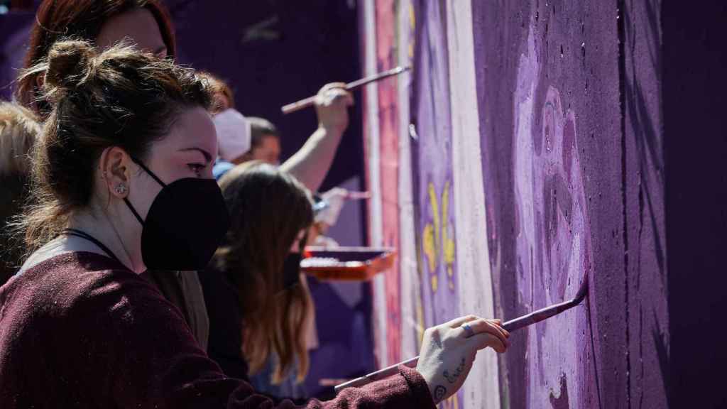 Varias personas pintan un mural feminista junto a la estación de Getafe Central, en Madrid, en marzo de 2021.