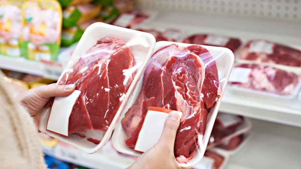 Una mujer compara el etiquetado de dos bandejas de carne en el lineal de un supermercado