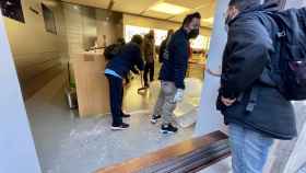 Operarios de limpieza y seguridad recogen los restos de cristal del interior de la tienda Apple de Valencia.