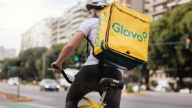 Un repartidor de Glovo montándose en su bicicleta.