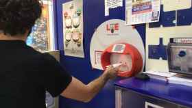 Un apostante valida su boleto en una Administración de Loterías
