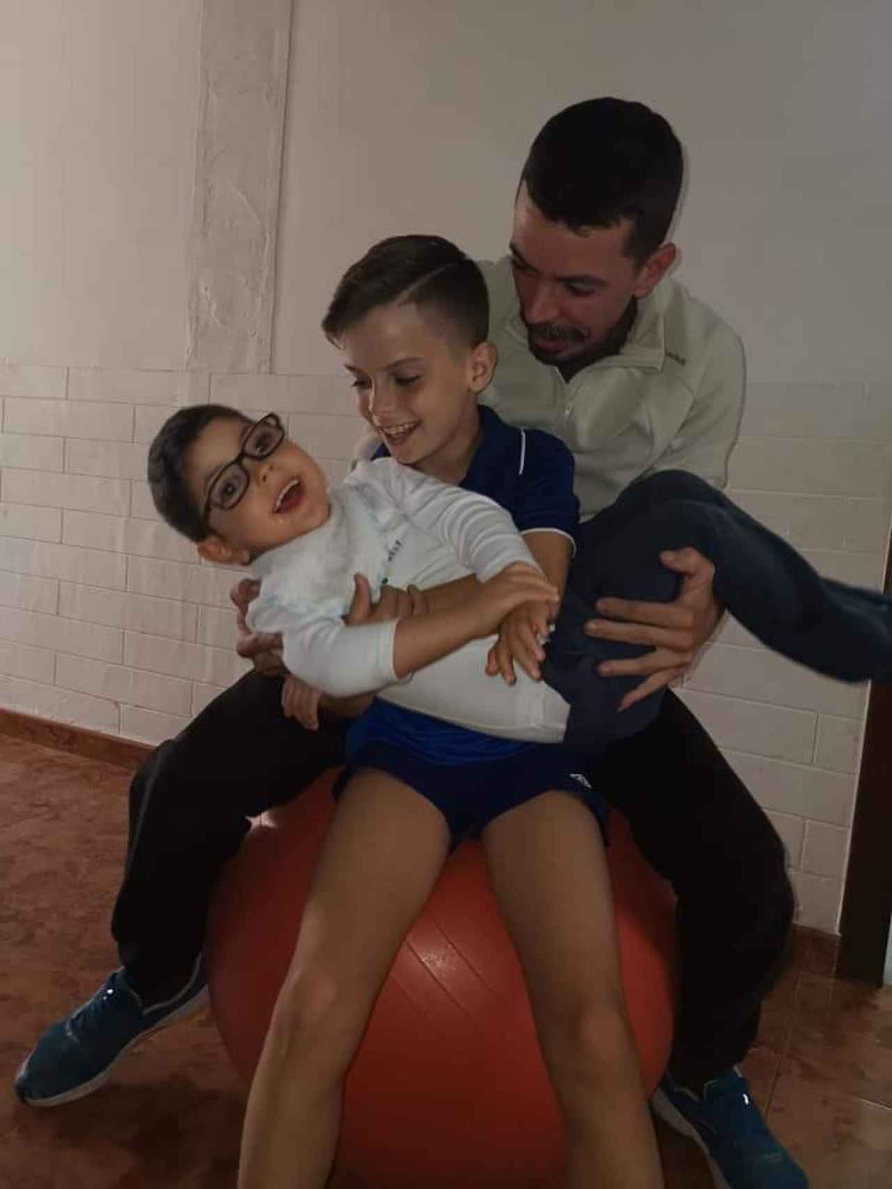 Eiden, sujetado en brazos por su hermano, Izan, y su padre, Francisco Manuel, sonrientes sobre una pelota hinchable.