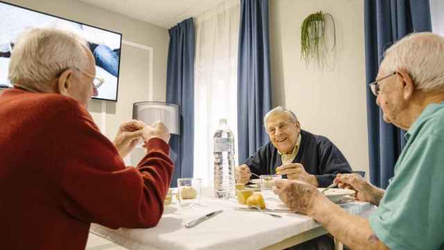 Tres hombres de avanzada edad comen en una residencia.