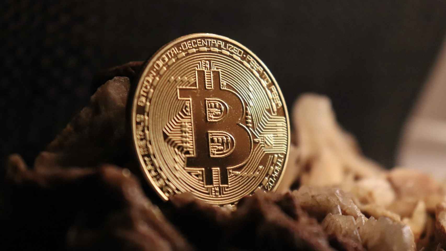 Una moneda que representa el bitcoin rompe un muro.
