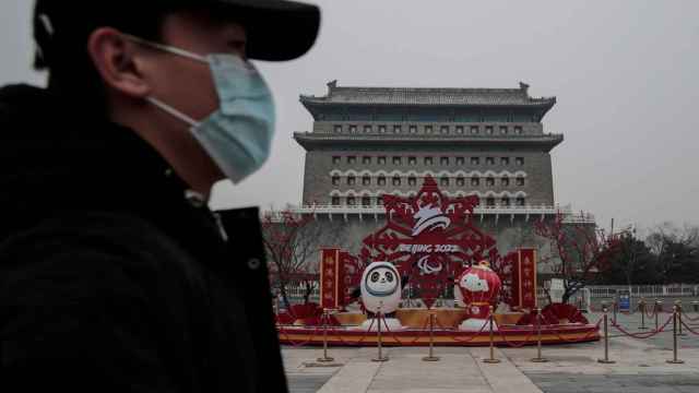 Un hombre con mascarilla delante de un mural que promociona los Juegos Olímpicos de Invierno de Pekín 2022