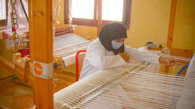 Una mujer tejiendo mandiles.