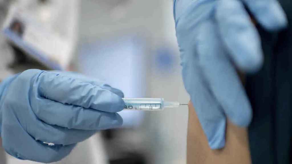 Un sanitario pincha una vacuna a un paciente.