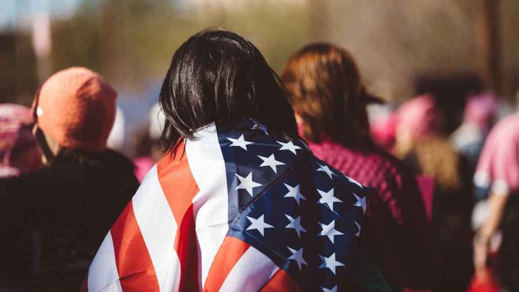 Una mujer latina lleva la bandera de Estados Unidos durante una concentración. Foto: Josh Johnson / Unsplash.